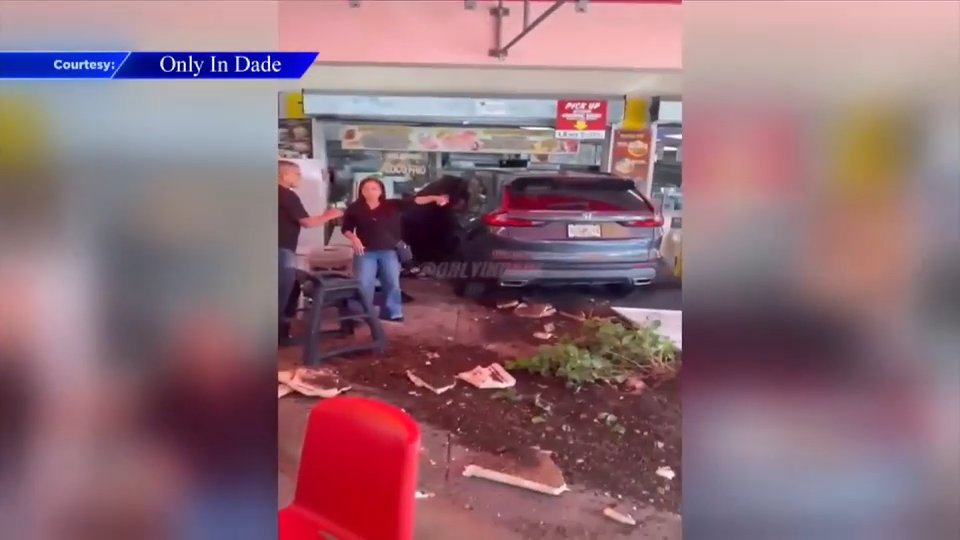 WSVN still of a dark Honda SUV through the El Palacio de los Jugos storefront in West Kendall