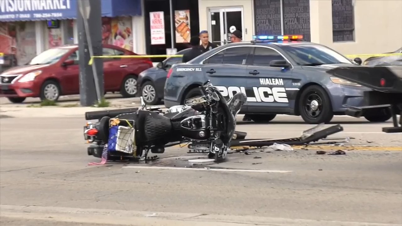 Hialeah Police at a wrong-way motorcycle crash scene on East 4th Avenue with the motorcycle on its side and yellow caution tape (no victim faces).